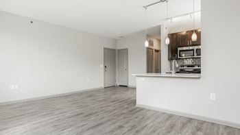 A spacious room with a kitchenette and a door leading to another room.